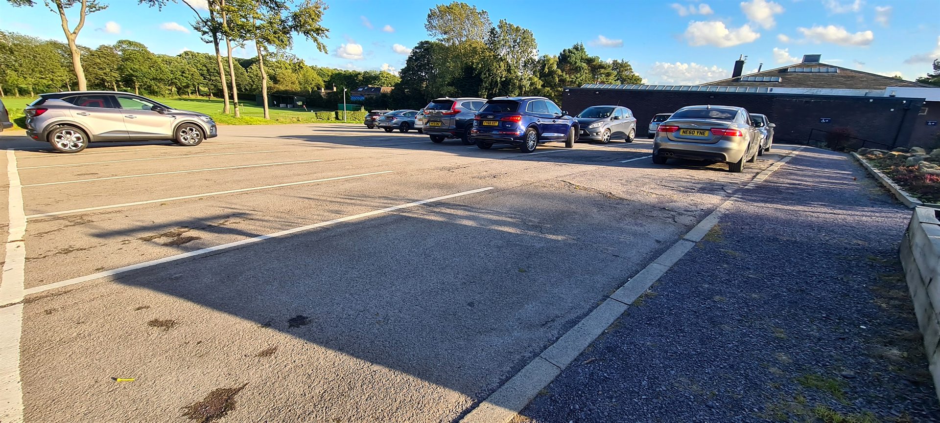 Vehicles parked on the worn Sand Moor Golf Club car park before works