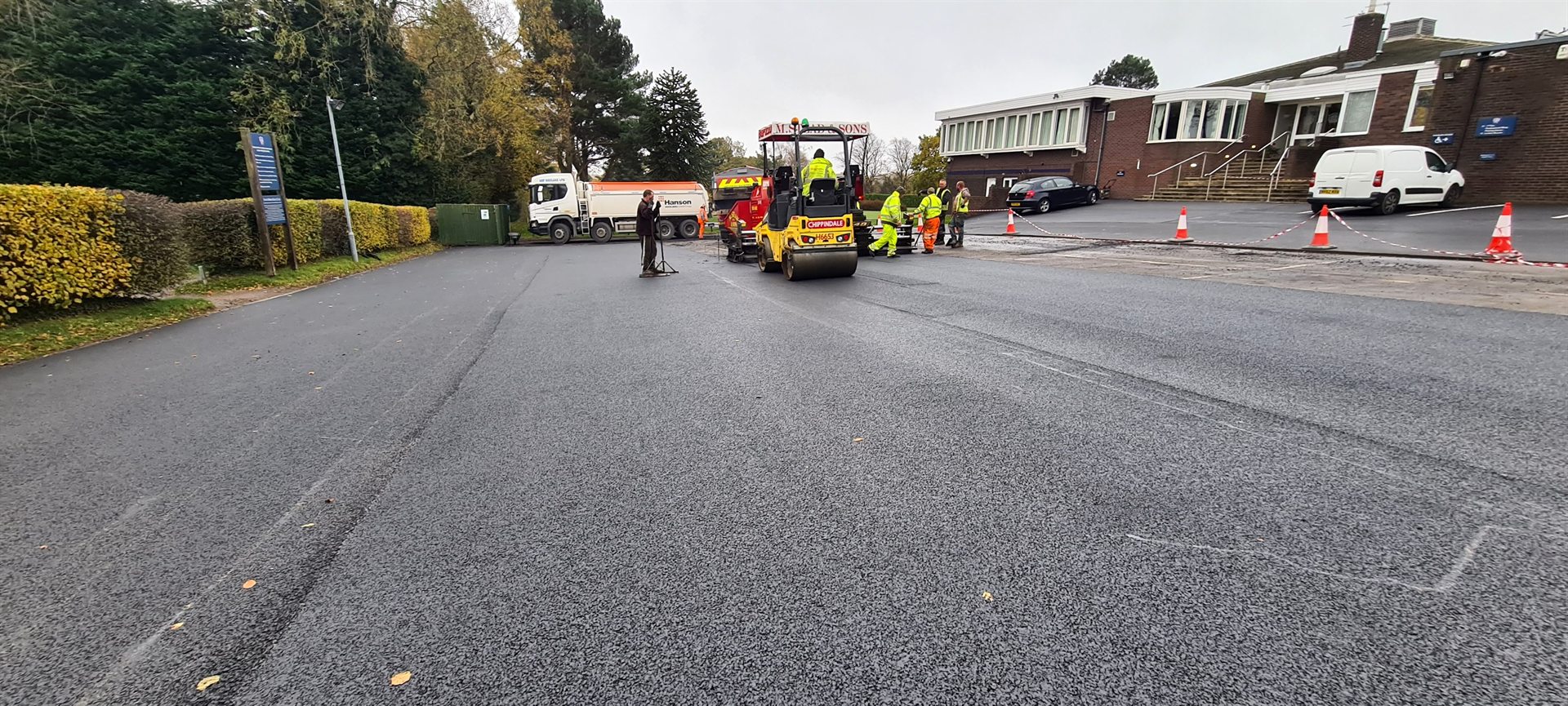 Steam rising from newly laid asphalt beside paving machinery